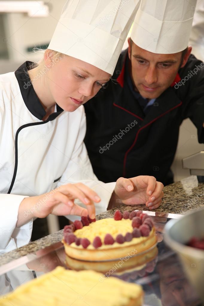 Pastry cook teaching student to make a cake