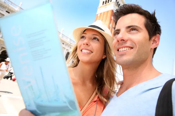 Paar lezen toeristische gids op san marco plaats — Stockfoto