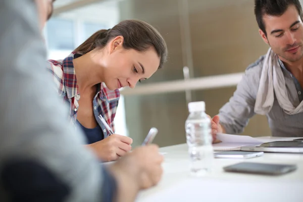 Students in class writing on notebooks — Stock Photo, Image