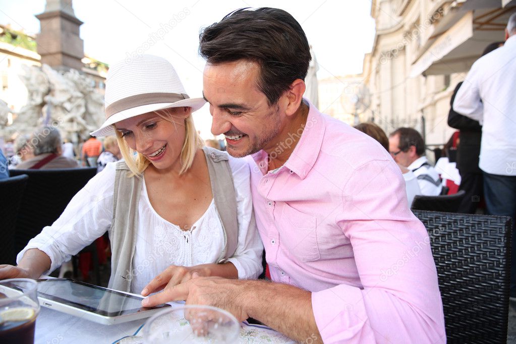 Tourists using tablet while having drink