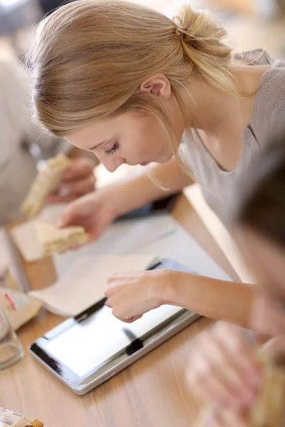 Kadın sandviç yeme ve tablet kullanarak iş başında — Stok fotoğraf