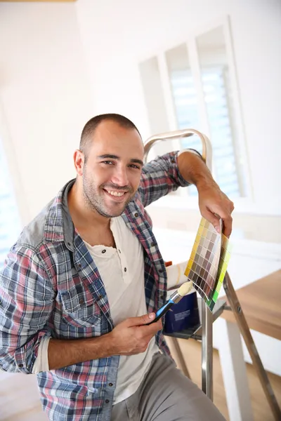 Guy dans un nouvel appartement à la recherche de couleurs de peinture — Photo