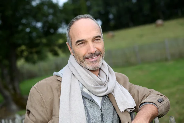 Senior man standing by fence — Stock Photo, Image