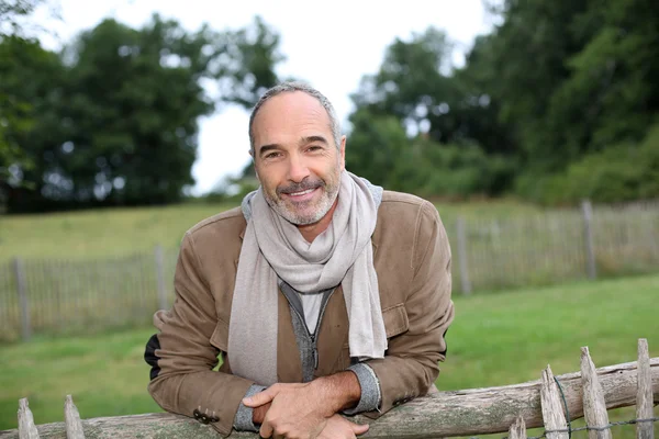 Senior man standing by fence — Stock Photo, Image