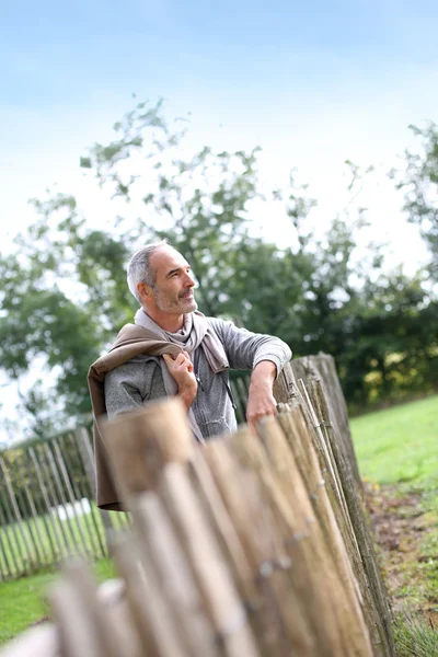Hombre maduro de pie junto a la cerca — Foto de Stock