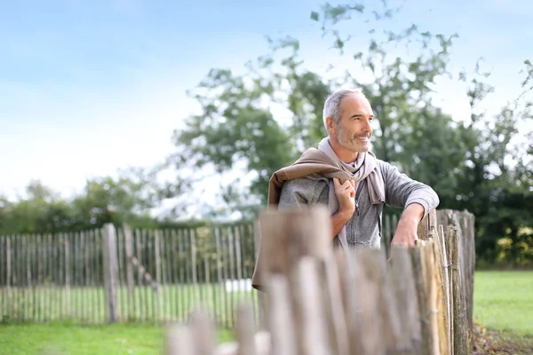 Mature man standing by fence — Stock Photo, Image