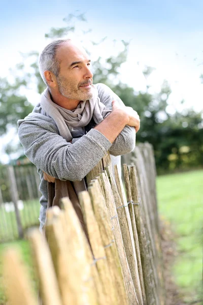 Hombre maduro de pie junto a la cerca — Foto de Stock