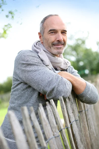 Mature man standing by fence — Stock Photo, Image