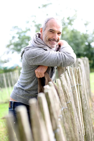 Mature man standing by fence — Stock Photo, Image