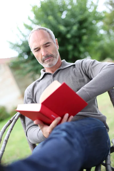 Uomo anziano che legge romanzo — Foto Stock