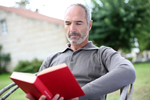 Hombre mayor leyendo novela — Foto de Stock