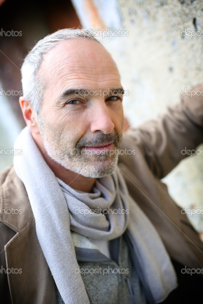Senior man leaning against wall
