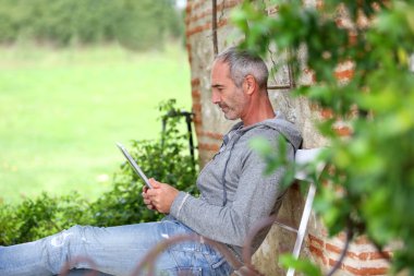 Olgun adam bir bankta tablet kullanma