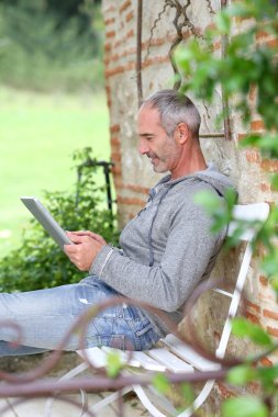 Olgun adam bir bankta tablet kullanma