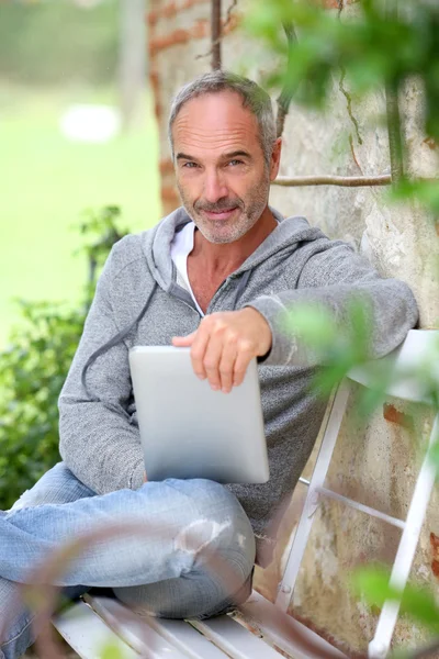 Зрелый человек с планшетом на скамейке — стоковое фото