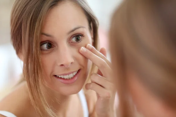 Chica poniendo crema anti-envejecimiento en su cara —  Fotos de Stock