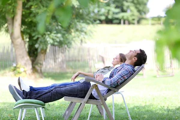 Couple relaxing in long chairs — Stock Photo, Image