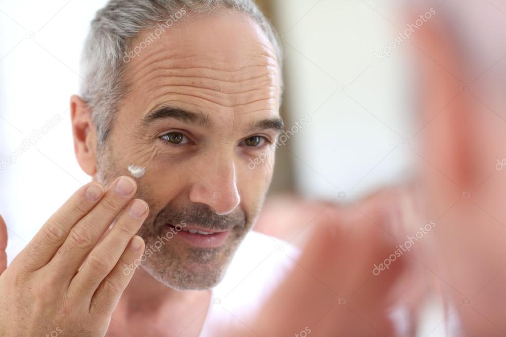 Mature man applying cosmetics