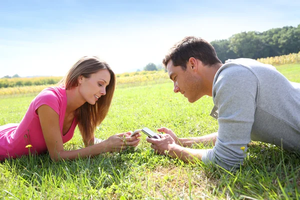 Pareja en el campo jugando con el teléfono inteligente —  Fotos de Stock