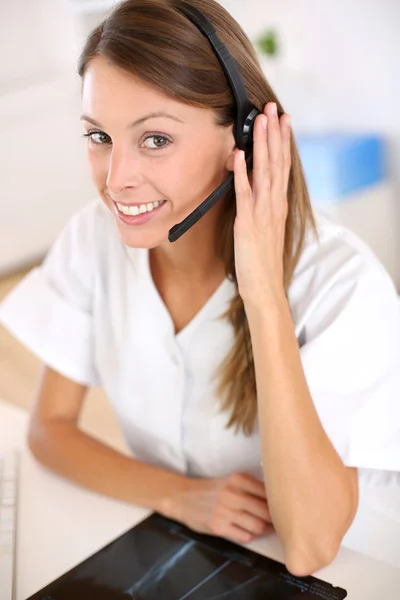 Enfermeira sorridente com fone de ouvido ligado — Fotografia de Stock