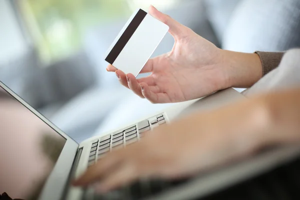 Mão segurando cartão de crédito e laptop — Fotografia de Stock