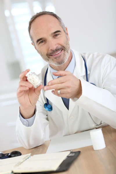 Médico sonriente sosteniendo pastillas — Foto de Stock