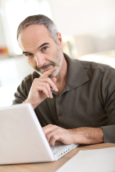 Sonriendo hombre mayor que trabaja con el ordenador portátil Imagen De Stock