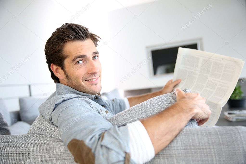 Smiling man reading newspaper