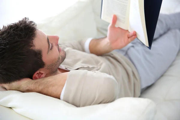 Uomo in divano lettura libro — Foto Stock