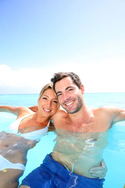 Couple swimming in infinity pool — Stock Photo, Image