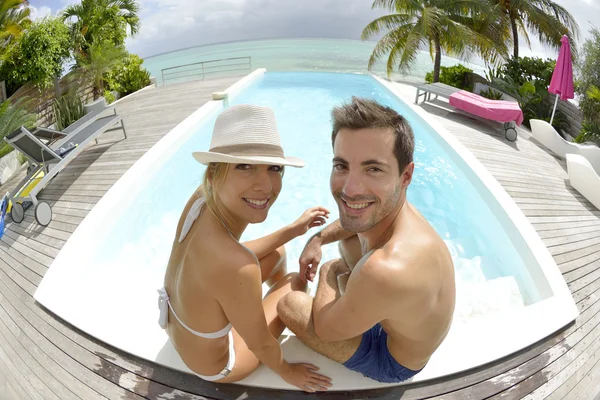 Couple sitting by swimming-pool — Stock Photo, Image