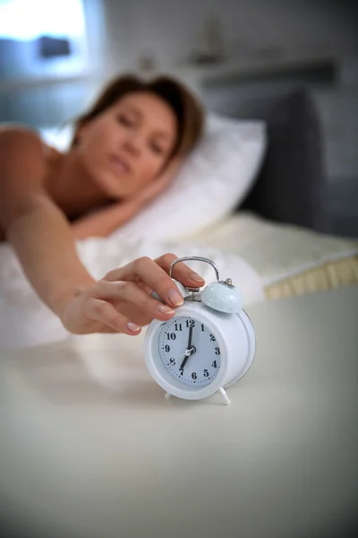 Woman turning alarm clock off — Stock Photo, Image