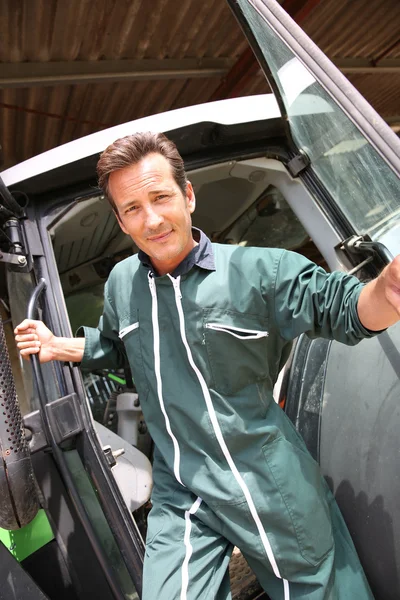 Smiling farmer getting out of tractor — Stock Photo, Image