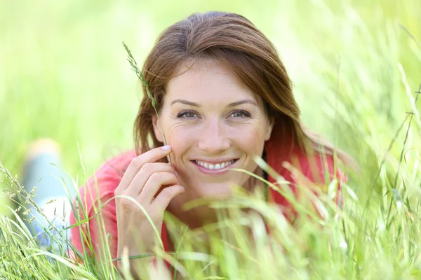Smiling woman laying in field — Stock Photo, Image