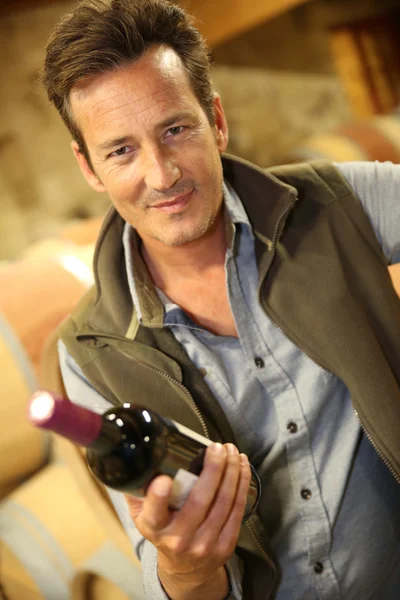 Winegrower holding bottle of wine — Stock Photo, Image