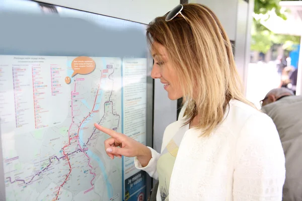 Mulher a olhar para o horário dos transportes — Fotografia de Stock