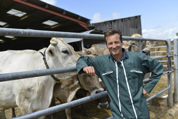Farmer leaned on fence by barn
