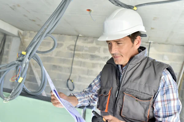 Worker checking blueprint on site — Stock Photo, Image