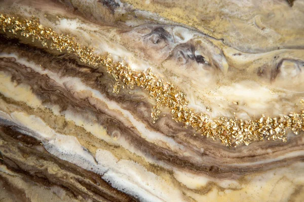 Abstract painting with epoxy resin. Marble streaks of gold,brown and beige . Abstract modern with streaks liquid background for design,close up.