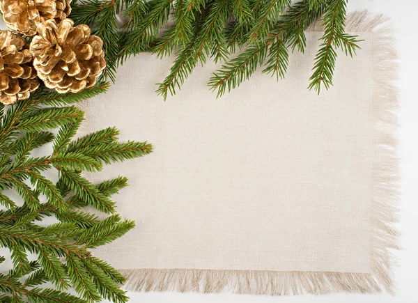 Moldura de Natal com conífera, tecido de linho e pinhas — Fotografia de Stock