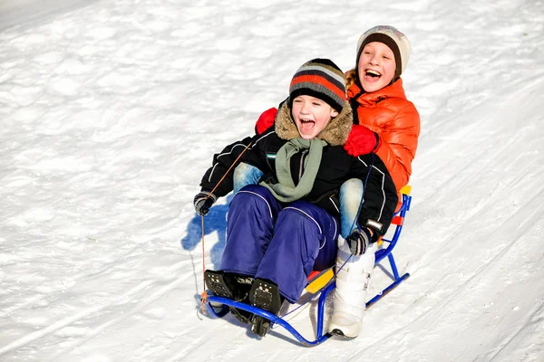 Liten pojke och flicka på släde vinter — Stockfoto