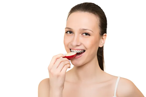 Mujer joven con paréntesis en los dientes comiendo manzana — Foto de Stock