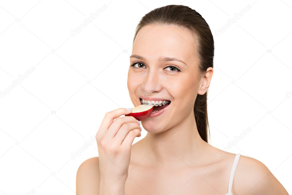 Young woman with brackets on teeth eating apple