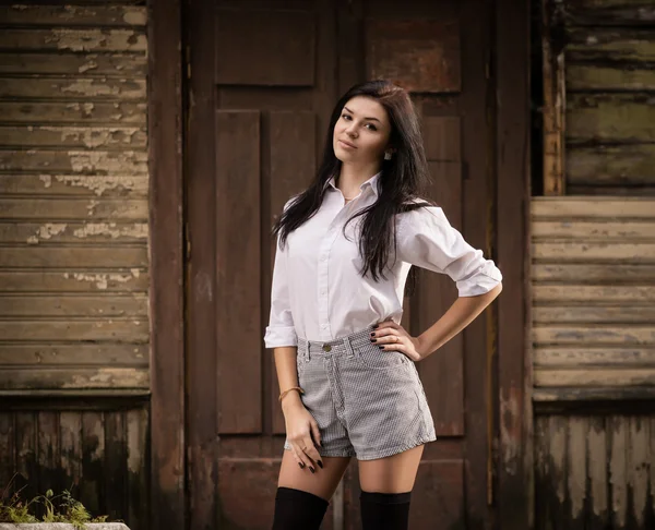 Fashion pretty young woman posing outdoor near a old wooden wall — Stock Photo, Image