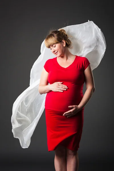 Porträt einer schönen Schwangeren im roten Kleid - Studioaufnahme — Stockfoto