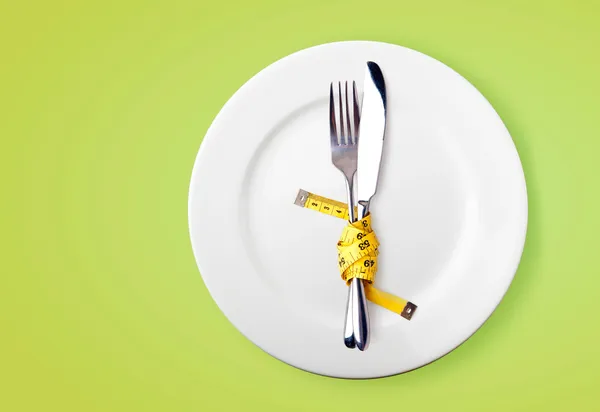 Cinta métrica en un tenedor y un cuchillo - imagen de concepto de dieta — Foto de Stock