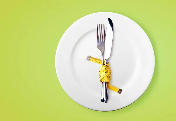 Cinta métrica en un tenedor y un cuchillo - imagen de concepto de dieta Imágenes de stock libres de derechos