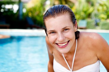 Tropik tatil köyünde havuz başında poz veren güzel genç bir kadın.