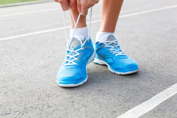 Närbild av ung kvinna knyta sport shoe — Stockfoto