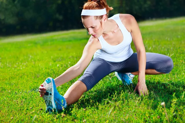 Young girl stretches before exercise in park — Stock Photo, Image